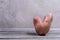 One non-standard ugly V-shaped fresh raw potato standing on grey wooden table on concrete wall background. Copy space