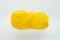 One oblong ball of yellow color in the center of the frame on a white woven background on the theme of handmade hobby knitting