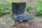 one old black torn leather boot stands on a gray stump