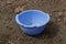 One old empty blue plastic broken bowl stands on the gray ground