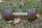 One old gray brown iron sports dumbbell lies in the grass