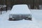 One old gray passenger car under white snow