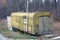 One old green iron trailer stands in dry grass and vegetation