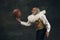 One old man, actor having fun, playing with basketball ball isolated on dark vintage background. Retro style, comparison