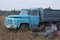 One old truck with a blue cabin is standing in the dry grass