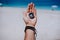 One open stretched hand palm with black metal compass on the sandy beach. Find your wish goal way concept. Blue sea in