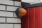 One orange plastic signal light hanging on a white brick wall