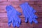 One pair of blue disposable medical gloves lies on a wooden background