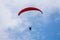 One paraglider in the blue sky with red parachute gliding for fun and excitement.