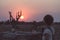 One person having a drink and looking at colorful sunset in the Namib desert, travel destination in Namibia, Africa. Concept of ad