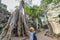 One person looking at Ta Prohm famous jungle tree roots embracing Angkor temples, revenge of nature against human buildings,