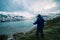 One person looking at trekking map, dramatic sky at dusk, lake and snowy mountains, nordic cold feeling