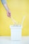 One person sorts recyclable materials on a yellow background into a special bin