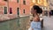 one person, woman 30 years old close-up. leaning on a brick wall, she looks at the Venetian canal. She is romantically