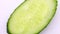 One piece of green cucumber cut oval rotate, top view, spinning slowly in a circle, close up.