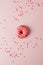 One pink live colar donut and heart shaped sprinkles on pink background, monochrome seet unhealthy food concept, flat lay, top