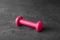 One pink vinyl dumbbell on grey table