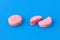 One pink whole tablet lies next to a broken one on a blue background.