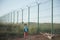 One poor little refugee orphan kid in dirty clothes standing near state border with high fence with razor barbed wire looking on