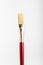 One professional artist paintbrush displayed vertically isolated on a white studio paper, photographed with soft focus