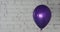 One purple balloon on bricky white wall background