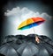 One rainbow umbrella standing out on a grey background.