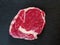 One; raw uncooked premium fresh rib eye steaks on a plastic tray, Top quality product from supermarket. On a slate stone table