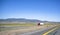 One red big rig semi truck with semi trailer driving on the divided road across plain prairie with mountains on the horizon