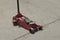 One red compact mechanical iron forklift with small black wheels