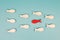 One red fish is swimming against the stream, opposite direction of the other fishes, being different, leadership and mindset