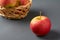 One red fresh whole ripe apple with vitamins on background of full wooden wicker basket