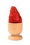 One red mellow strawberry in eggcup over white