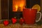 One red mug with christmas hearts and fireplace