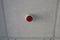 One red round plastic alarm on the gray ceiling