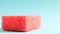 One red sponge on a blue background is used to wash and erase the dirt used by housewives in everyday life. They are made of