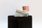 One ringgit banknote of Malaysia and mini Malaysian nation flag stick on the black wallet with white background