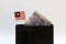 One ringgit banknote of Malaysia and mini Malaysian nation flag stick on the black wallet with white background