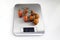 One ripe branch of cherry tomatoes is weighed on a kitchen scale