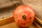 One ripe juicy pomegranate on a wooden tray against a background of rough homespun fabric. Close up