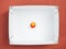 One ripe nectarine in a white cardboard box, top view. Delivery of products. Product leftovers after delivery. Dark red background