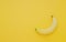 One ripe sweet testy banana on yellow background top view with c