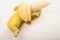 One ripe yellow partially peeled banana on a white background. Close up