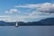 One sailing boat on water with lefkas shore mountains and clouds