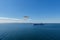 One seagull in flight with ship, blue cloudy sky and sea