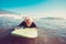 One senior trying surfing alone in the water of the beach and learning surf - mature old man waiting for the waves with his long