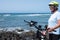 One senior woman with gray hair leaning her bicycle. Blue sky and sea. Enjoying e bike activity for healthy lifestyle. Waves and