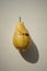 One shabby yellow pear on a white sunny table