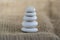 One simplicity stones cairn on jute brown background, group of five light gray pebbles built in tower