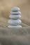 One simplicity stones cairn on jute brown background, group of five light gray pebbles built in tower