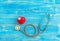 One single alone red heart love shape hand exercise ball with bandage MD medical doctor physician`s stethoscope blue wood backgro